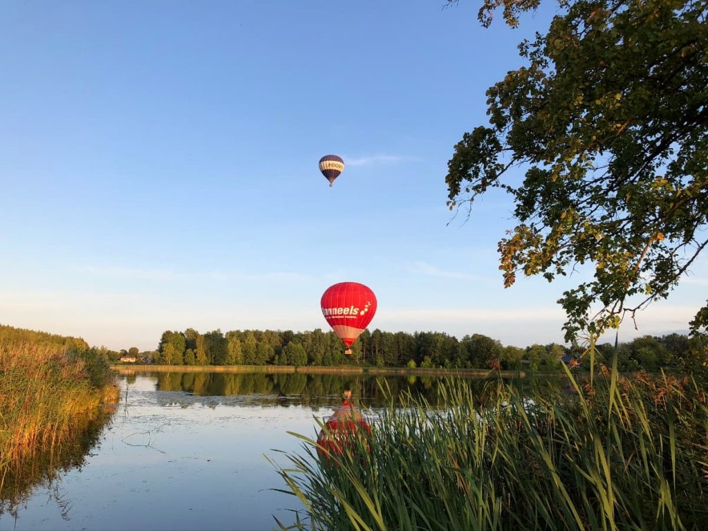 Du oro balionai skrenda virš ežero